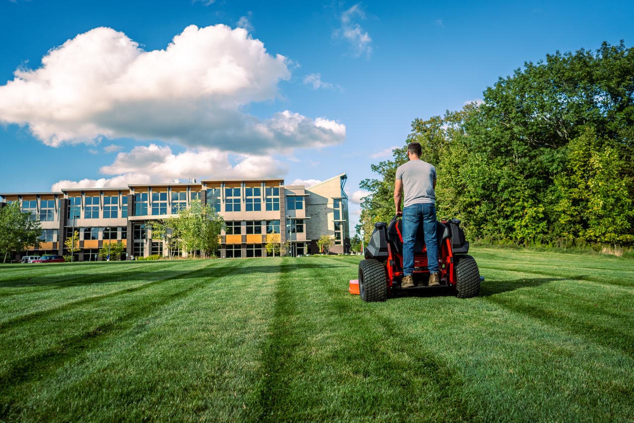 Lawn care professional mowing a commercial property with a stand-on mower